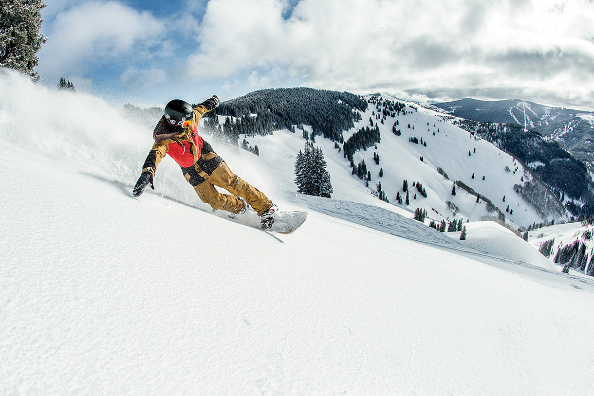 Snowboarder going downhill on snowy mountain